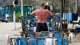 Seorang pria bersiap untuk berlatih mengangkat beban di outdoor gym atau pusat kebugaran terbuka di tepi Sungai Dnipro, Kiev, Ukraina, Kamis (18/4). Pusat kebugaran ini dibangun karena minimnya fasilitas olahraga yang terjangkau oleh warga. (AP Photo/Efrem Lukatsky)