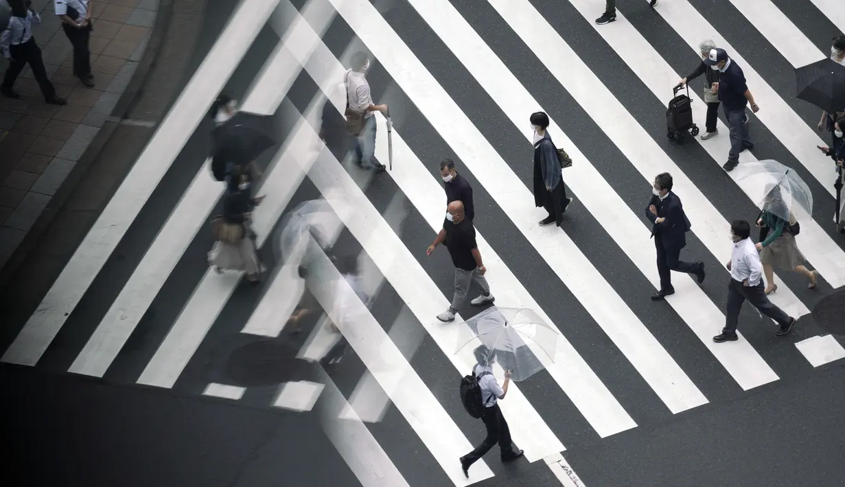Orang-orang memakai masker untuk membantu mencegah penyebaran virus corona berjalan di penyeberangan pejalan kaki di Tokyo, (23/9/2020). Badai tropis di Samudra Pasifik perlahan mendekati wilayah Tokyo pada hari Rabu. (AP Photo/Eugene Hoshiko)