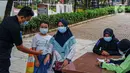 Petugas mengecek suhu tubuh warga yang masuk Taman Puring, Jakarta, Minggu (14/3/2021). Dinas Pertamanan dan Hutan Kota Provinsi DKI Jakarta akan terus mengevaluasi setiap pekan untuk menentukan, apakah kebijakan membuka Ruang Terbuka Hijau akan diteruskan atau tidak. (Liputan6.com/Faizal Fanani)