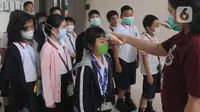 Murid Sekolah Dasar (SD) mendapatkan pemeriksaan suhu tubuh di Jakarta Nanyang School (JNY) di BSD, Tangerang Selatan, Selasa (3/3/2020). Sebelum masuk area sekolah, seluruh siswa wajib menjalani pemeriksaan suhu tubuh untuk mengantisipasi penyebaran virus Corona. (merdeka.com/Arie Basuki)