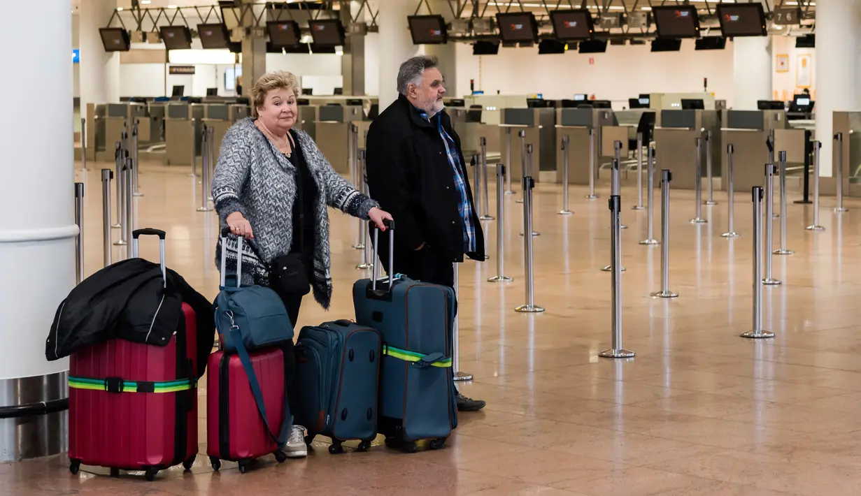 Dua penumpang menunggu informasi ketika mereka berada di Bandara Brussels, Zaventem, Belgia, Rabu (13/2). Penutupan lalu lintas udara Belgia dimulai sejak Selasa 12 Februari 2019 pukul 22.00 waktu setempat. (AP Photo/Geert Vanden Wijngaert)