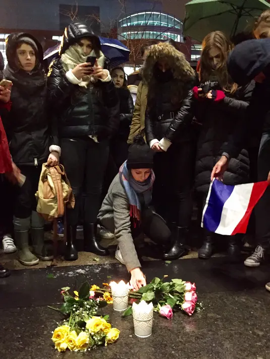 Sejumlah warga berkumpul di pusat kota Montreal, Jumat (13/11/2015). Karangan bunga tersebut untuk menghormati para korban serangan mematikan di Paris. (AFP Photo/ Marc Braibant)