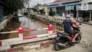 Pengendara motor melintas dekat bantaran Kali Induk Kramat Jati, Jakarta, Rabu(18/5/2022). Pemprov DKI Jakarta melalui Dinas Sumber Daya Air (SDA) berencana akan menormalisasi Kali Induk secara keseluruhan guna mencegah banjir yang melanda kawasan tersebut saat hujan deras mengguyur. (Liputan6.com/FaizaL Fanani)