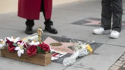 Orang-orang menaruh bunga pada bintang Sidney Poitier di Hollywood Walk of Fame di Hollywood, California, Jumat (7/1/2022). Poitier, bintang film kulit hitam pertama Hollywood dan pria kulit hitam pertama yang memenangkan aktor terbaik Oscar, meninggal pada usia 94 tahun. (VALERIE MACON/AFP)
