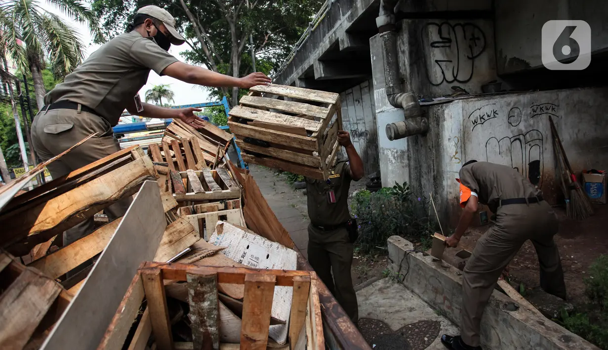 Petugas Satpol PP merapikan barang milik tunawisma di bawah flyover Jatinegara, Jakarta Timur, Senin (19/7/2021). Hal ini juga untuk mencegah terjadinya penyebaah virus Covid-19. (Liputan6.com/Johan Tallo)