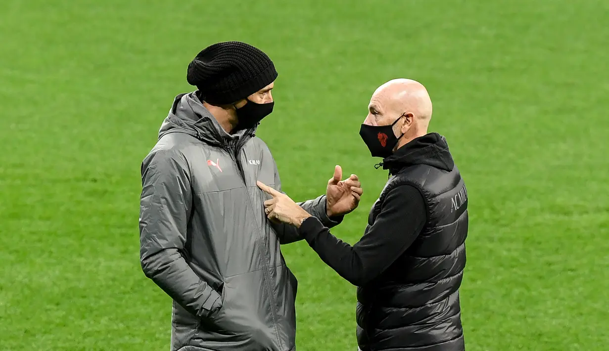 Penyerang AC Milan, Zlatan Ibrahimovic (kiri) berbincang  dengan pelatih Stefano Pioli di lapangan di Stadion Wanda Metropolitano di Madrid, Spanyol (23/11/2021). Diketahui, AC Milan kini berada di dasar klasemen dengan mengoleksi  satu poin. (AFP/Oscar Del Pozo)