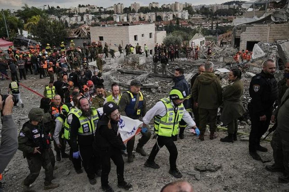 Petugas penyelamat dan personel militer mengangkat jenazah korban di lokasi serangan rudal Iran di Beit Shemesh, Israel, Minggu (1/3/2026), setelah beberapa orang tewas akibat serangan tersebut. (Dok. AP/Leo Correa)