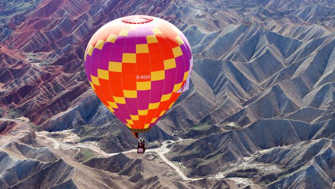 Sebuah balon udara terbang di langit Taman Geologi Nasional Danxia di Zhangye, Provinsi Gansu, China barat laut, pada 26 Juli 2020. Sebuah festival balon udara internasional dibuka di Zhangye pada Minggu (26/7). Total 100 balon udara akan ditampilkan dalam festival tersebut. (Xinhua/Cheng Lin)