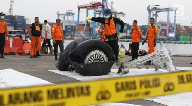 Petugas menyemprot cairan pada bagian roda pesawat Lion Air PK-LQP JT 610 di Pelabuhan JICT 2, Jakarta, Senin (5/11). Bagian tersebut dipindah untuk dilakukan identifikasi dan pengecekan lebih lanjut oleh KNKT. (Liputan6.com/Helmi Fithriansyah)