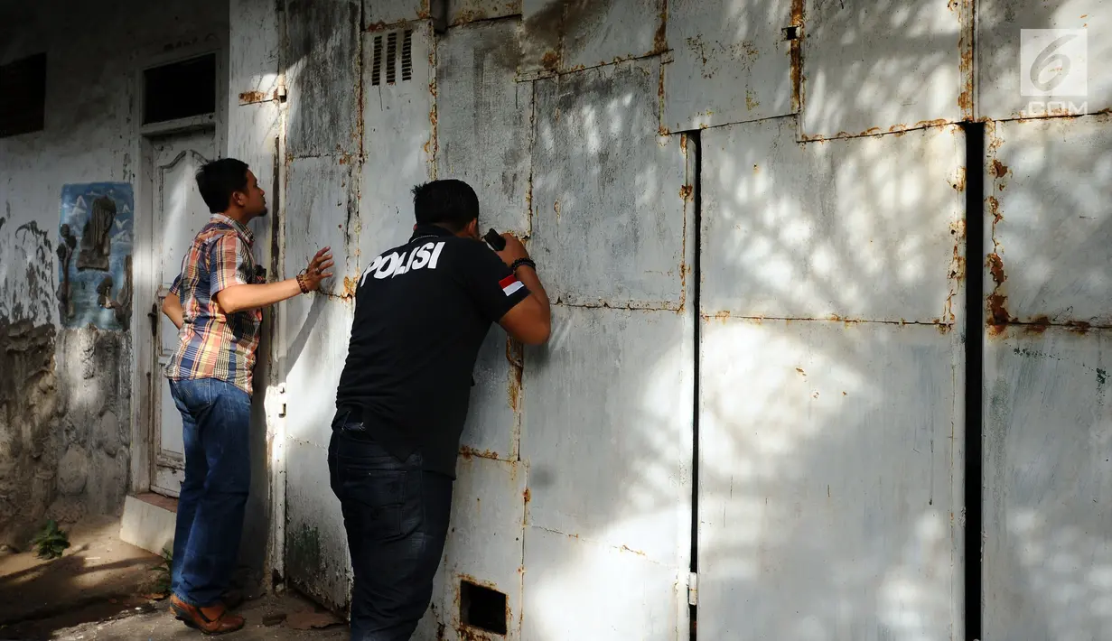 Petugas melakukan pengintaian rumah terduga penampung TKI Ilegal di Jalan Percetakan Negara X, Jakarta, Rabu (31/5). Dengan membawa satu tersangka, petugas Dirtipidum Mabes Polri melakukan pencarian barang bukti baru. (Liputan6.com/Helmi Fithriansyah)