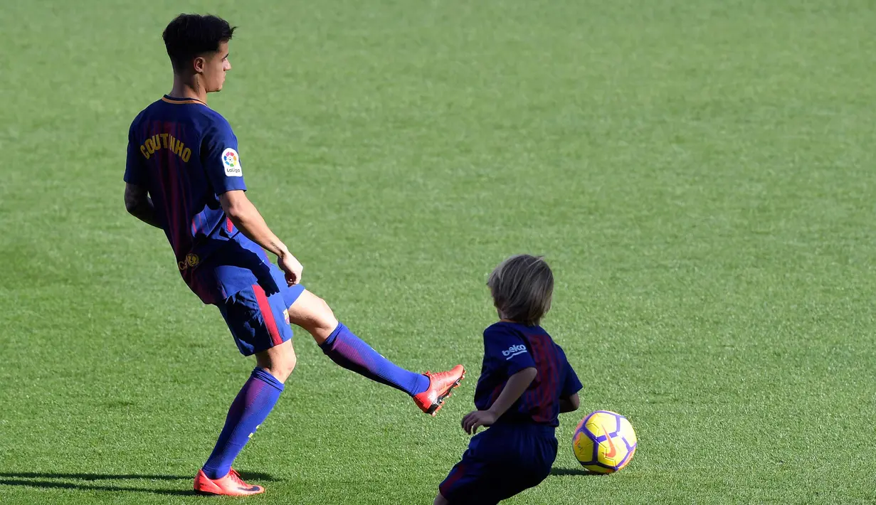 Gelandang baru Barcelona, Philippe Coutinho bermain bola dengan anak-anak saat perkenalan dirinya di Nou Camp, Barcelona (8/1). Coutinho diboyong Barcelona dengan harga sebesar 400 juta euro (sekitar Rp 6,45 triliun). (AFP Photo/Lluis Gene)