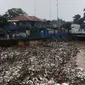 Bus Transjakarta melintasi tumpukan sampah di Pintu Air Manggarai, Jakarta, Rabu (24/4). Tingginya curah hujan di Bogor membuat sampah yang berasal kebanyakan dari sampah rumah tangga ini terbawa arus sungai menumpuk di Pintu Air Manggarai. (Liputan6.com/Johan Tallo)