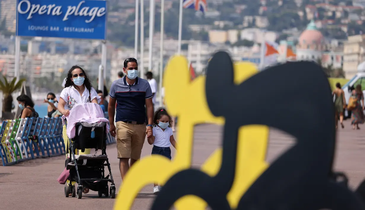 Orang-orang melintasi logo balap sepeda Tour De France 2020 di kota Nice, French Riviera, Rabu (26/8/2020). Ajang balap sepeda lintas kota di Prancis kali ini akan dimulai dari kota Nice pada 29 Agustus hingga 20 September di bawah bayang-bayang ‘gelombang kedua’ COVID-19. (Kenzo Tribouillard/AFP)