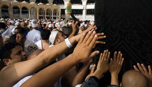 Umat muslim memanjatkan doa di dekat pintu Kabah dengan menyentuhnya selama menjalani ibadah umrah di Masjidil Haram, Mekkah, 4 Mei 2018. Banyak umat muslim yang menyambut bulan Ramadan dengan menjalankan ibadah umrah ke tanah suci. (AP Photo/Amr Nabil)