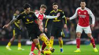 Pemain Manchester United, Lisandro Martinez, melindungi bola dari hadangan pemain Arsenal, Martin Odegaard, dalam pertandingan Liga Inggris di Emirates Stadium, Minggu (25/1/2026) malam WIB. (AP Photo/Kirsty Wigglesworth)