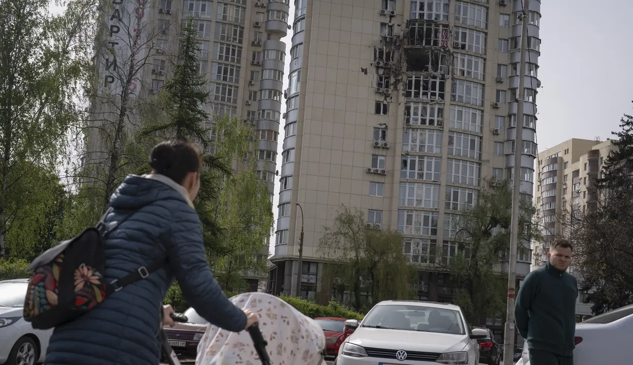 Orang-orang melewati sebuah gedung apartemen yang rusak akibat drone yang ditembak jatuh, selama serangan semalam Rusia, di Kyiv, Ukraina, Senin, 8 Mei 2023. (AP Photo/Andrew Kravchenko)