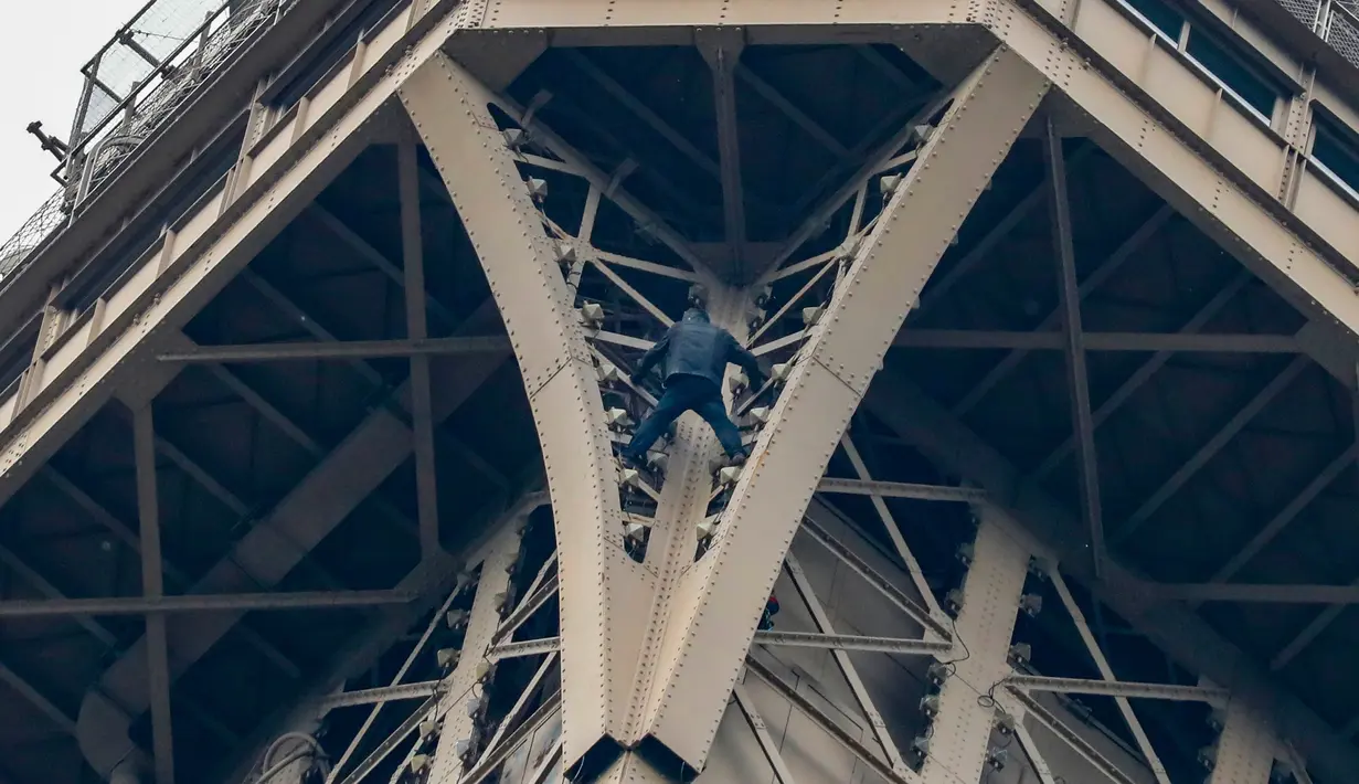 Seorang pria tak dikenal nekat memanjat Menara Eiffel tanpa peralatan keselamatan di Paris, Senin (20/5/2019). Tim pemadam kebakaran termasuk seorang spesialis pendakian berada di lokasi dan menghadapi penyusup itu yang motivasinya masih belum diketahui. (FRANCOIS GUILLOT / AFP)