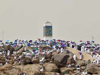 Jemaah haji berkumpul di sekitar Jabal al-Rahma (Gunung Rahmat) saat menunaikan prosesi wukuf di Padang Arafah, tenggara Kota Suci Mekah, Arab Saudi, Senin (19/7/2021). Wukuf di Padang Arafah menjadi puncak ibadah selama prosesi haji. (FAYEZ NURELDINE/AFP)