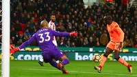 Gelandang Liverpool, Sadio Mane berlari melewati kiper Stoke City, Lee Grant untuk mencetak gol pada pekan ke-14 Premier League di Bet365 Stadium, Kamis (30/11). Liverpool berhasil membantai Stoke City dengan skor 3-0. (Geoff CADDICK/AFP)