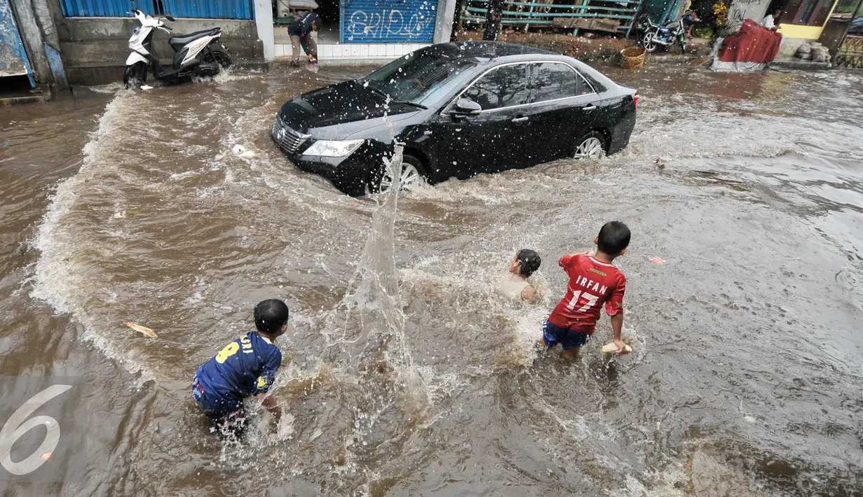 Sejumlah anak di kawasan Kemang Utara memanfaatkan banjir untuk bermain, Jakarta, Rabu (20/7). Akibat intensitas hujan deras yang mengguyur Jakarta, sejumlah ruas jalan tergenang air. (Liputan6.com/Yoppy Renato)