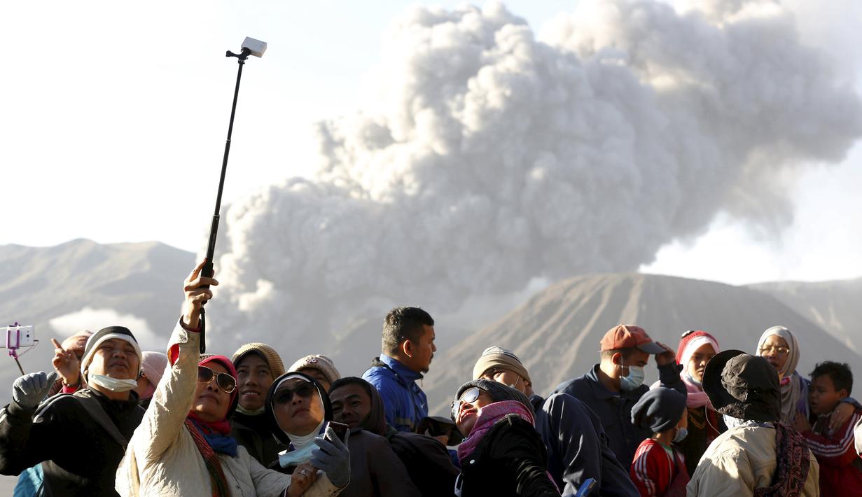 Wisatawan berfoto dengan latar belakang semburan abu vulkanik dari Gunung Bromo yang sedang erupsi di Ngadisari, Probolinggo, Jawa Timur, Rabu (6/1/2016). (REUTERS/Darren Whiteside)