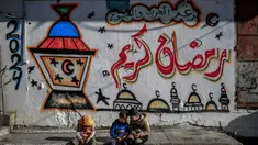 Anak-anak Palestina duduk di depan tembok dengan gambar bertema Ramadan di Kota Gaza pada 8 Maret 2024. (Foto: AFP)