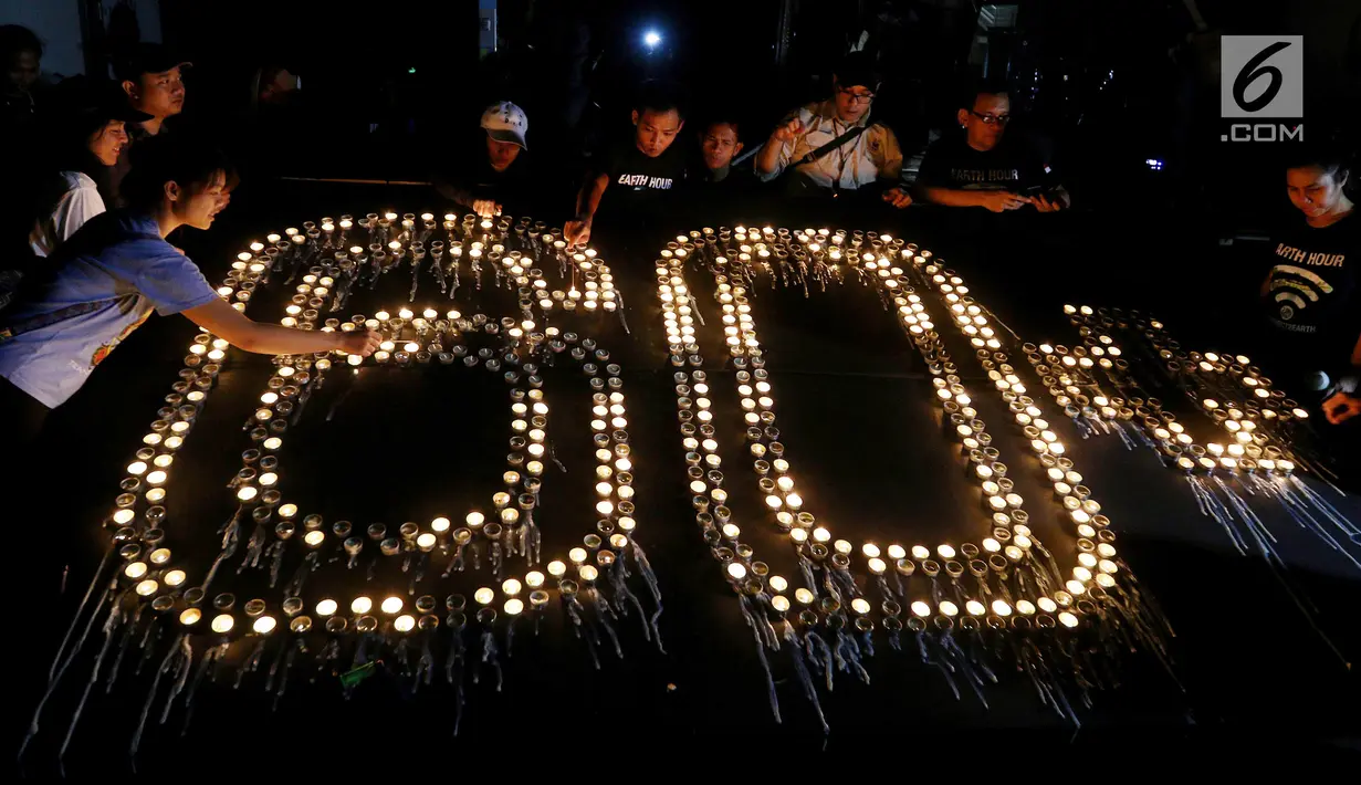 Sejumlah warga menyalakan lilin berbentuk 60+ pada peringatan Earth Hour 2018 di Jakarta, Sabtu (24/3). Sebanyak 7 ikon kota Jakarta ikut serta dalam peringatan Earth Hour. (Liputan6.com/Johan Tallo)