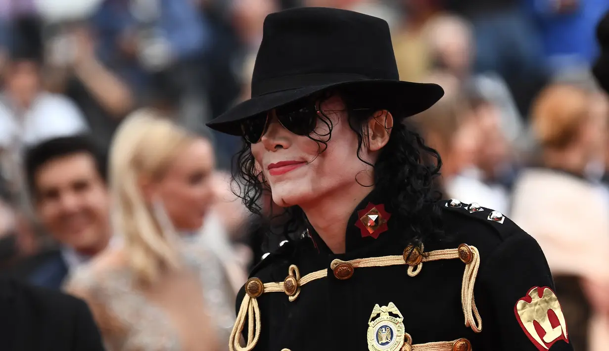 Pria berpenampilan Michael Jackson berpose di karpet merah pemutaran film Solo: A Star Wars Story pada Festival Film Cannes, Selasa (15/5). Kehadiran pria mirip mendiang raja musik pop dunia tersebut mengundang perhatian. (AFP/Anne-Christine POUJOULAT)