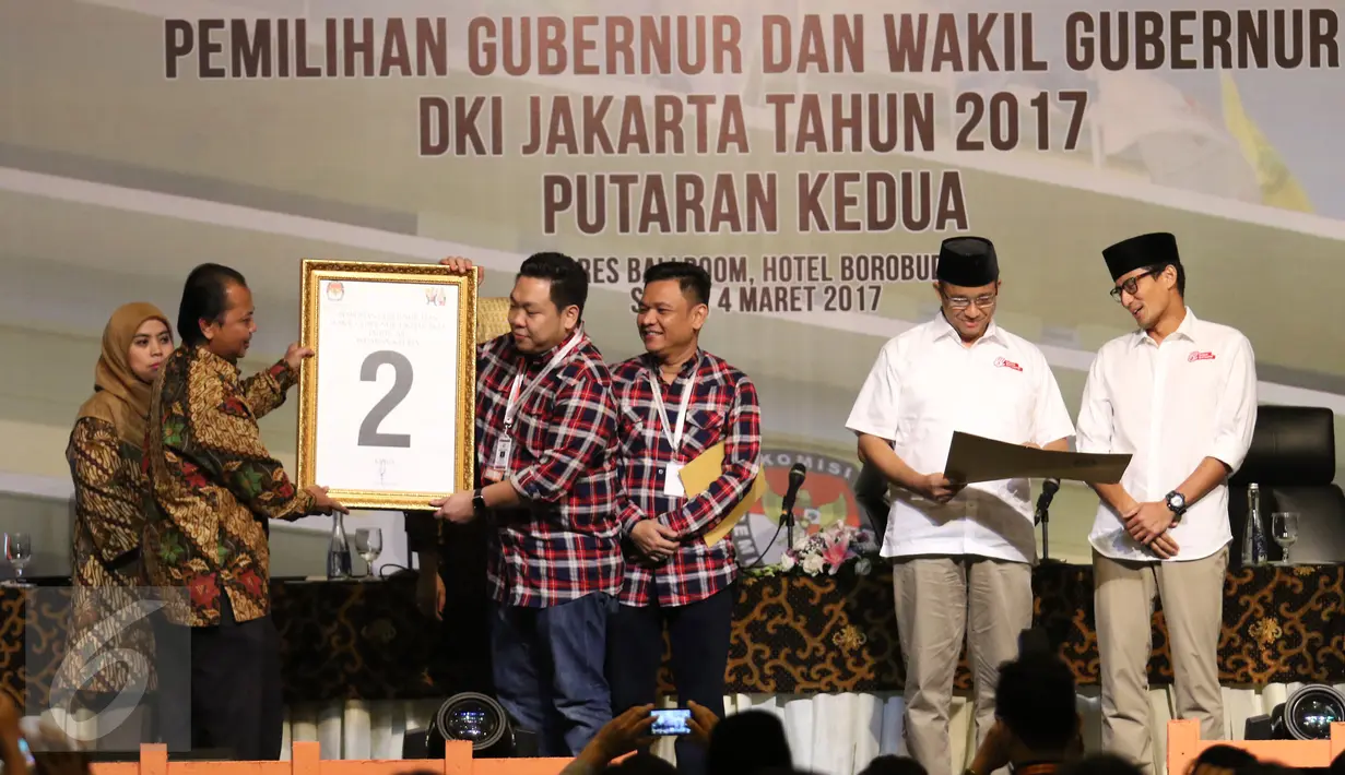 Perwakilan dari cagub dan cawagub no. 2 Pasangan Basuki Tjahaja Purnama atau Ahok dan Djarot Saiful Hidayat menerima plakat yang diberikan oleh ketua KPU DKI Jakarta, Sumarno saat rapat pleno terbuka di Jakarta, Sabtu (5/3). (Liputan6.com/Angga Yuniar)