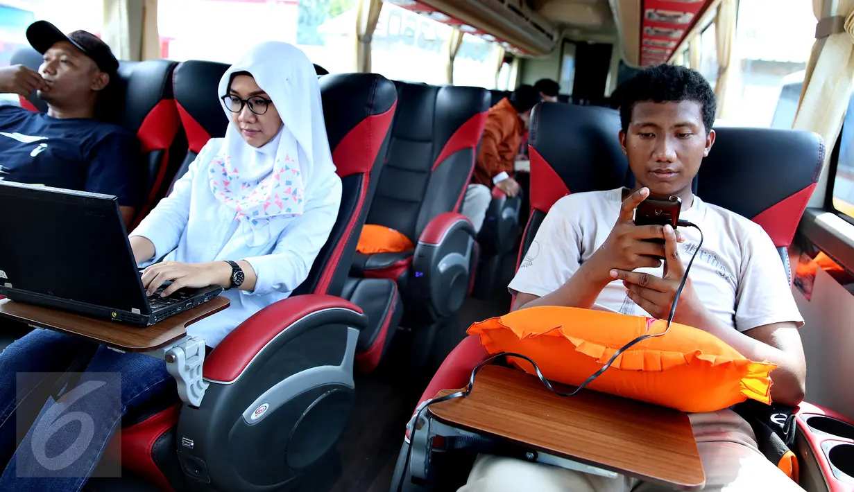 Penumpang Bus Harapan Jaya menggunakan laptop dan charger handphone yang merupakan fasilitas bus di Pool Ciputat, Tangerang Selatan. Penumpang bisa menggunakan fasilitas seperti wi fi, charger listrik dan USB. (Liputan6.com/Fery Pradolo)