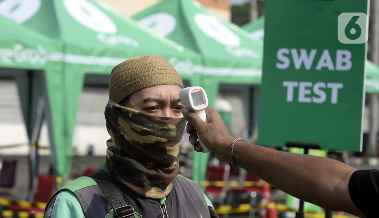 Pengemudi ojek online dicek suhu tubuhnya saat menjalani swab test COVID-19 di Alam Sutra, Tangerang Selatan, Banten, Selasa (21/7/2020). Swab test gratis yang digelar Pemerintah Provinsi Banten melalui Dinas Kesehatan tersebut diikuti oleh 700 pengemudi ojek online. (merdeka.com/Dwi Narwoko)