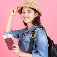Seorang perempuan mengenakan pakaian berlibur dan memegang paspor (Foto Dok: Freepik/jcomp).