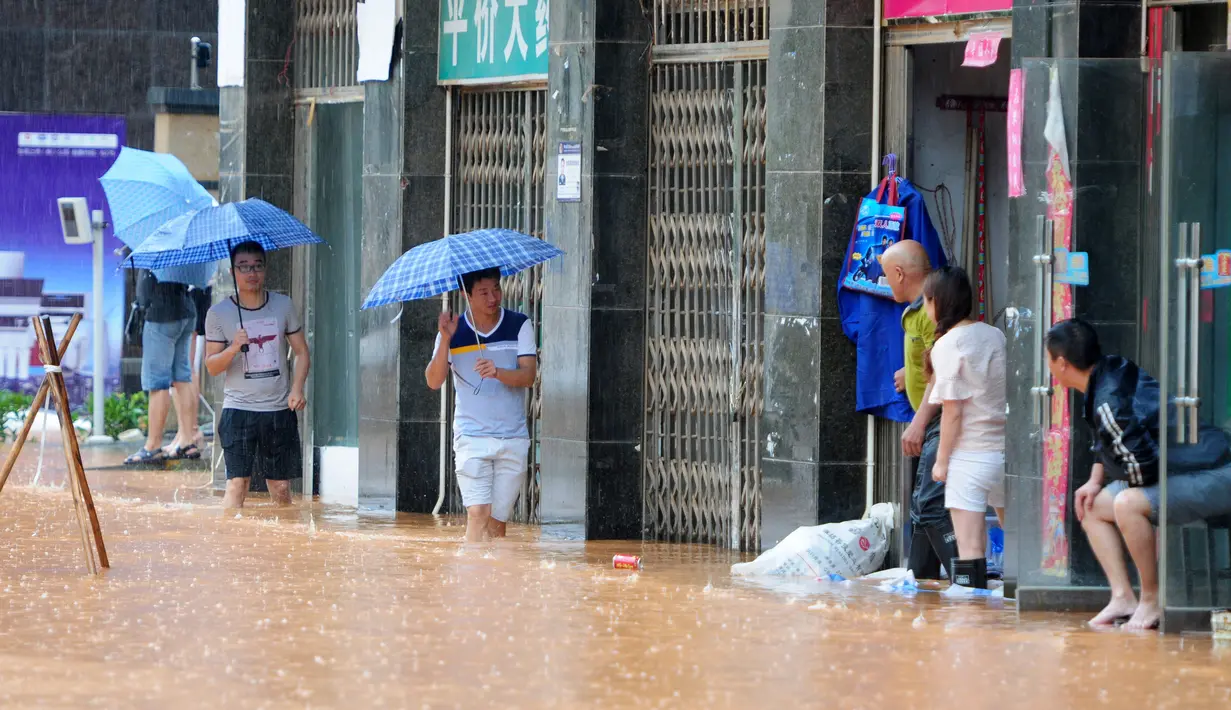 Warga saat beraktivitas melewati jalanan yang banjir di Jiujiang , Provinsi Jiangxi , Cina , (19/2). Banjir yang tinggi menyendat lalu lintas Kota Jiujiang. (REUTERS/ China Daily)