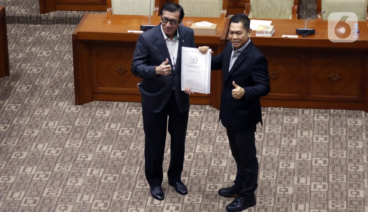 Wakil Ketua Komisi III DPR Adies Kadir (kanan) menyerahkan Daftar Invetarisasi Masalah (DIM) kepada Menteri Hukum dan Hak Asasi Manusia Yasonna Laoly saat rapat kerja di Jakarta, Kamis (31/3/2022). Rapat terkait amandemen Undang-Undang No.35/2009 tentang Narkotika. (Liputan6.com/Angga Yuniar)