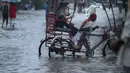 Seorang penarik becak membawa penumpang melewati genangan air saat hujan turun di Guwahati, negara bagian Assam, India, Kamis (16/6/2022). Guwahati telah menerima curah hujan 81,5 mm dalam 24 jam terakhir yang termasuk dalam kategori 'hujan lebat' dalam 24 jam terakhir. (AP Photo/Anupam Nath)