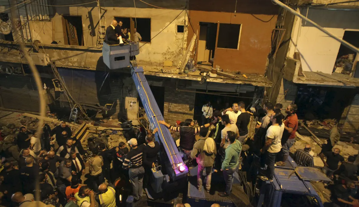 Petugas dibantu warga menggunakan alat berat untuk memeriksa lokasi ledakan dua bom bunuh diri di Beirut, Lebanon, Kamis (12/11). Sedikitnya 37 orang tewas dan lebih dari 181 terluka dalam ledakan bom bunuh diri ini. (REUTERS / Khalil Hassan)