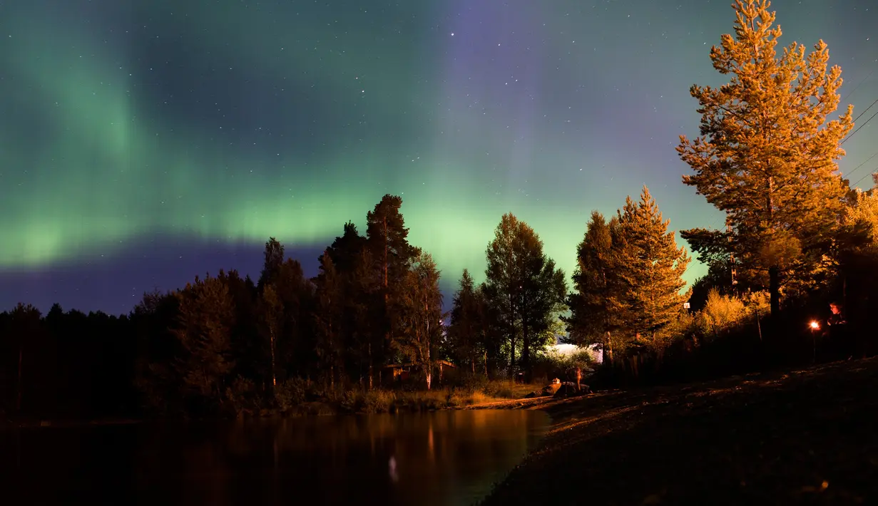 Pancaran cahaya aurora borealis menghiasi Desa Erikslund di Vasternorrland County, Swedia (23/8). Fenomena alam yang indah ini terjadi pada bulan Maret-April dan September-Oktober. (AFP PHOTO/ JONATHAN NACKSTRAND)