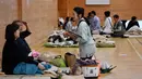 Pejabat kota Koriyama memeriksa kesehatan penduduk yang dievakuasi di tempat penampungan di dalam sebuah sekolah dasar di Koriyama, prefektur Fukushima (14/10/2019). Sedikitnya 43 orang tewas akibat dilandan Topan Hagibis. (AFP Photo/Jiji Press)