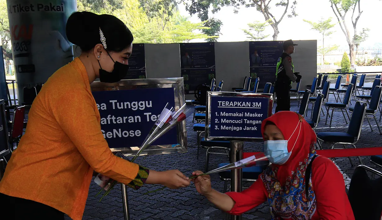 Petugas PT KAI Daop 1 Jakarta membagikan bunga kepada penumpang di Stasiun Gambir, Rabu (21/4/2021). PT KAI DAOP 1 memperingati Hari Kartini menginspirasi para penumpang agar semangat berjuang melawan pandemi COVID-19 dengan selalu menerapkan protokol kesehatan. (Liputan6.com/Herman Zakharia)