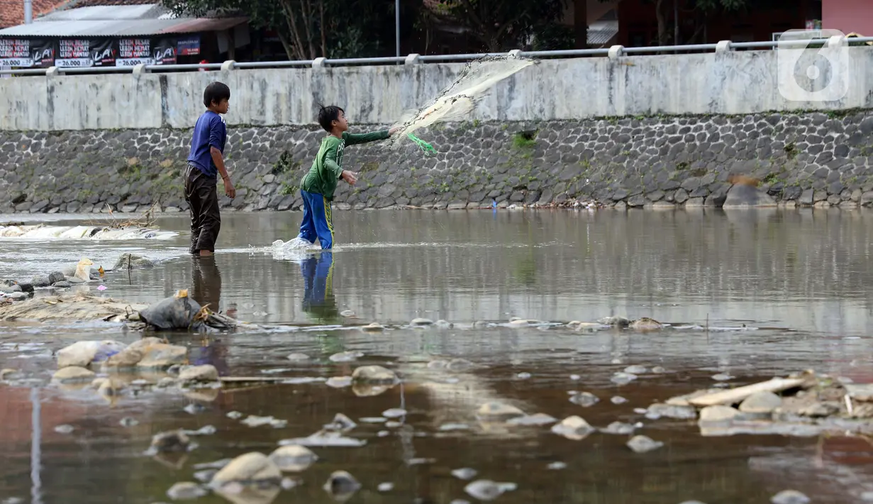 Dua orang anak menjala ikan di area Bendung Katulampa, Kota Bogor, Jawa Barat, Senin (3/8/2020). Debit air sungai Ciliwung di Bendung Katulampa yang mengalami penyusutan sejak satu bulan terakhir dimanfaatkan anak-anak untuk bermain air dan layangan. (Liputan6.com/Helmi Fithriansyah)