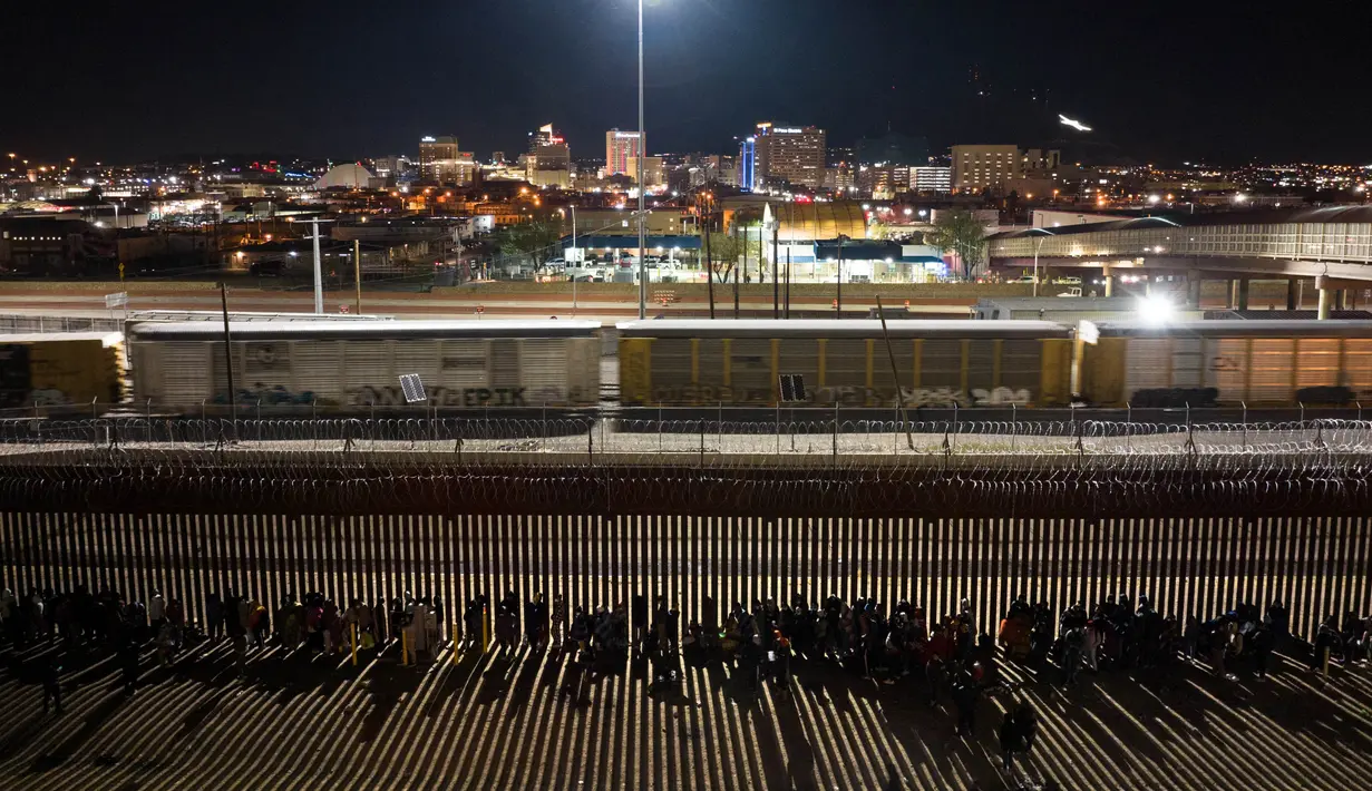 Migran bermalam di luar pagar perbatasan AS-Meksiko sambil menunggu pengajuan suaka di El Paso, Texas, di Ciudad Juarez, Meksiko, Rabu (21/12/2022).  Akibatnya Gubernur Texas Greg Abbott memerintahkan 400 tentara ke perbatasan AS-Meksiko di El Paso, yang berada dalam keadaan darurat karena gelombang migran yang menyeberang dari Meksiko ke kota. (JOHN MOORE / GETTY IMAGES NORTH AMERICA / Getty Images via AFP)