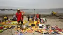 Seorang dukun menggelar ritual dengan meletakkan sejumlah poster bergambar para pemimpin dunia di Pantai Agua Dulce di Lima, Peru, (29/12). Para dukun ini meramalkan AS akan diselimuti dengan malapetaka dan kesuraman pada 2017. (Reuters/Mariana Bazo)