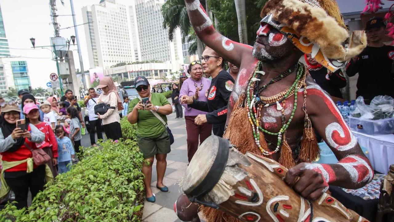 Warga suku Papua sedang melakukan aksi menabuh gendang saat mengkampanyekan Sail Teluk Cenderawasih di Kawasan Thamrin, Jakarta, Minggu (8/10/2023).