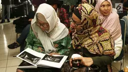 Bunda Ifet melihat buku "Tanpa Batas" fotografer Tjandra Moh Amin, Jakarta (14/12). Tjandra mencoba menerjemahkan kehidupan Slank secara utuh, menguak sisi humanisme personil  Slank yang jarang tersentuh media tanah air. (Liputan6.com/Herman Zakharia)