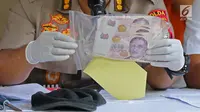 Kabid Humas Polda Metro Jaya Kombes Pol Argo Yuwono  menunjukkan barang bukti uang dolar Singapura saat rilis di Polda Metro Jaya, Jakarta, Rabu (19/6/2019). (Liputan6.com/Herman Zakharia)
