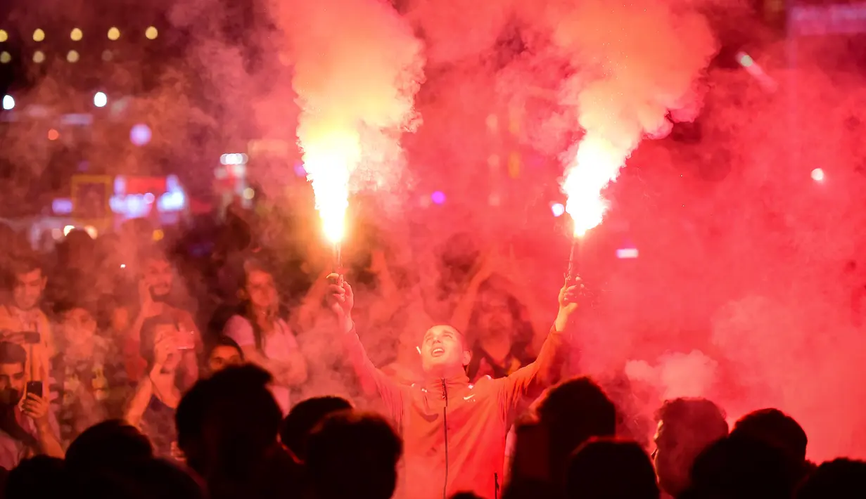Suporter Galatasaray menyalakan flare saat merayakan kemenangan timnya meraih gelar Liga Turki usai pertandingan melawan Istanbul Basaksehir di Turk Telekom Arena di Istanbul (19/5/2019). Galatasaray memastikan gelar liga Turki ke-22 usai mengalahkan Istanbul Basaksehir 2-1. (AFP Photo/Yasin Akgul)