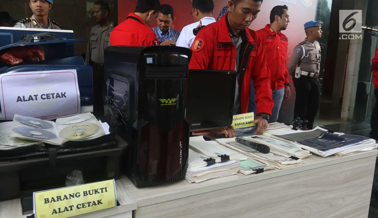Petugas menata barang bukti pada rilis kasus pemalsuan dokumen dan uang palsu di Jakarta, Rabu (20/12). Bareskrim Polri menyita dokumen palsu yaitu 20 BPKB, 32 STNK, 76 lembar cek fisik kendaraan, 20 KTP dan tiga buku tabungan. (Liputan6.com/Angga Yuniar)