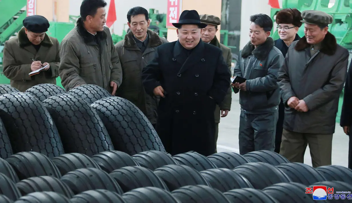 Pemimpin Korut, Kim Jong-un berbincang dengan para pekerja di pabrik ban lokal di di Chagang, Korut (3/11). Kim Jong-un tampil dengan mengenakan jas dan topi hitam saat mengunjungi pabrik ban tersebut. (KCNA/via AP)
