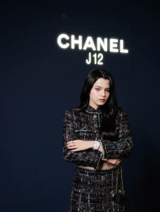 Becky Rebecca tampil dengan setelan hitam tweed dari Chanel, dari atasan blazer dan mini skirt. Sambil membawa sling bag mini. Ia mengenakan jam tangan putih Chanel.  Dok.CHANEL