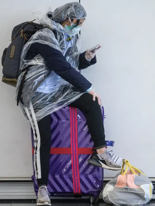 Penumpang memakai mantel plastik untuk mengantisipasi penyebaran virus corona Covid-19 di Bandara Internasional Hong Kong, Hong Kong (19/3/2020). (AFP/Anthony Wallace)